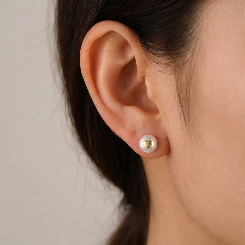 The Golden Heart pearl stud earring worn on the ear with a freshwater pearl and polished gold-plated heart detail
