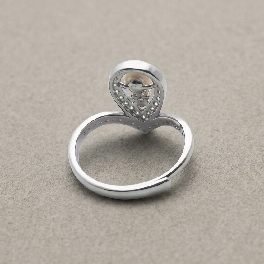 Silver ring with a heart-shaped diamond on a beige background
