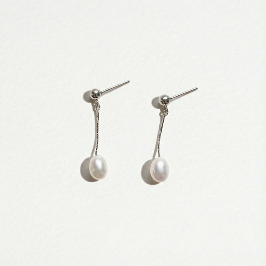 Front view of The Ethereal Drop pearl drop earrings in sterling silver with freshwater pearls on a light background