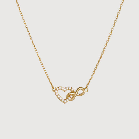 Gold necklace with heart and infinity symbol on a light gray background