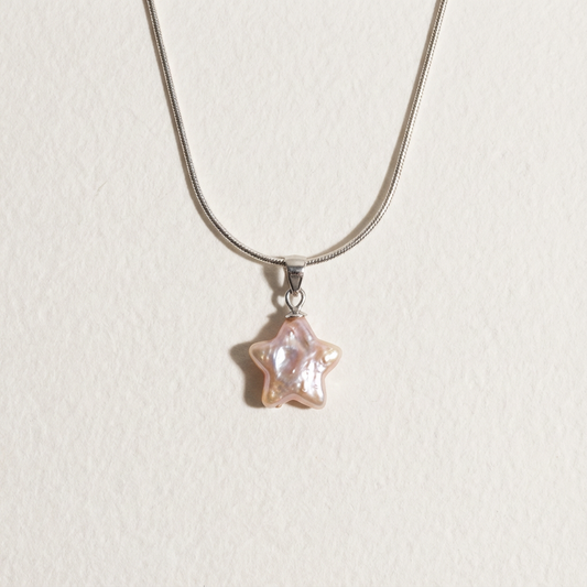 Pink star-shaped baroque pearl pendant necklace in sterling silver on a light beige background