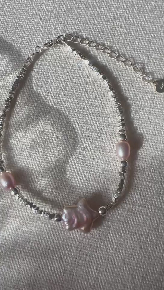 Video of The Lavender Star baroque pearl and star charm bracelet on a light fabric background