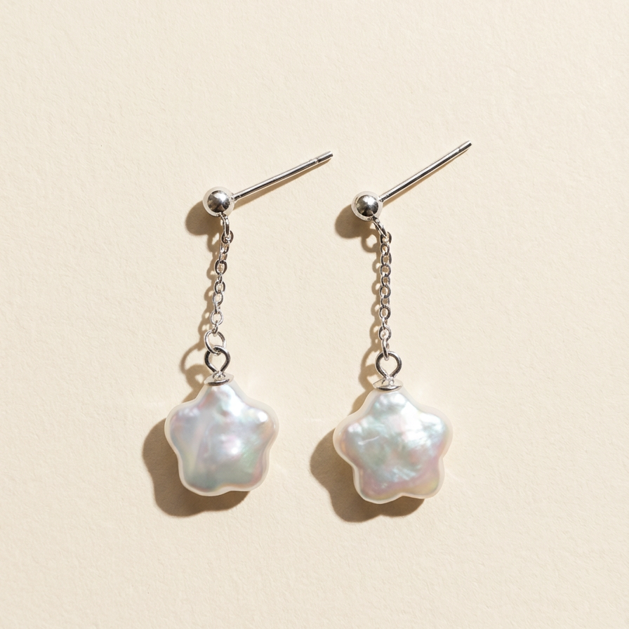 Star baroque freshwater pearl drop earrings in sterling silver on a light beige background