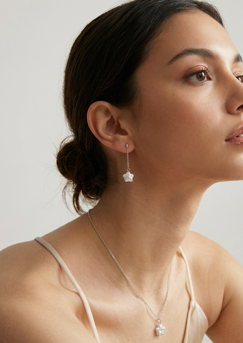 Model wearing the star baroque freshwater pearl necklace and drop earrings set in sterling silver against a light neutral background