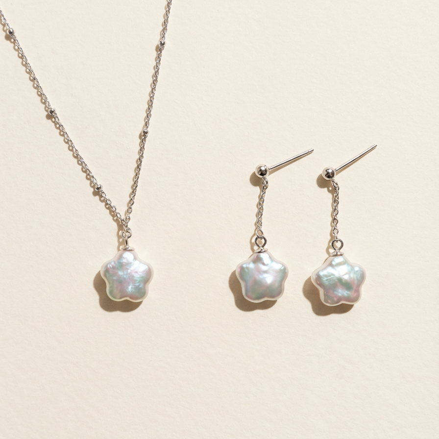 Matching star baroque freshwater pearl necklace and drop earrings set in sterling silver on a light beige background