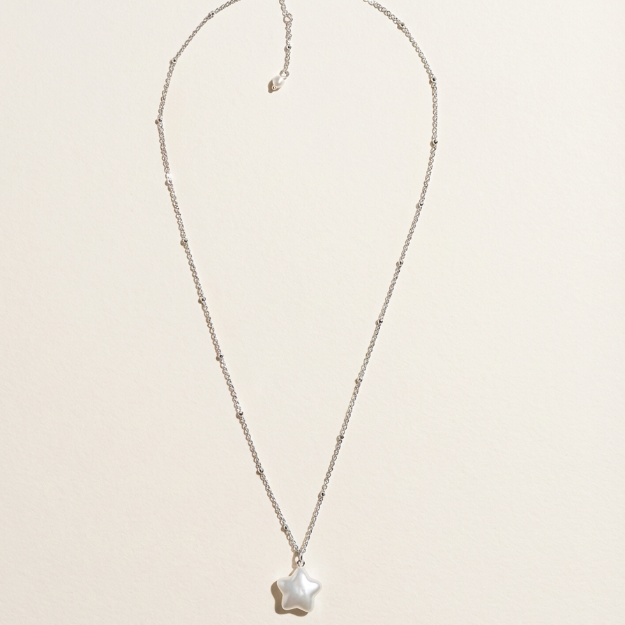 Star baroque freshwater pearl pendant necklace in sterling silver on a light beige background
