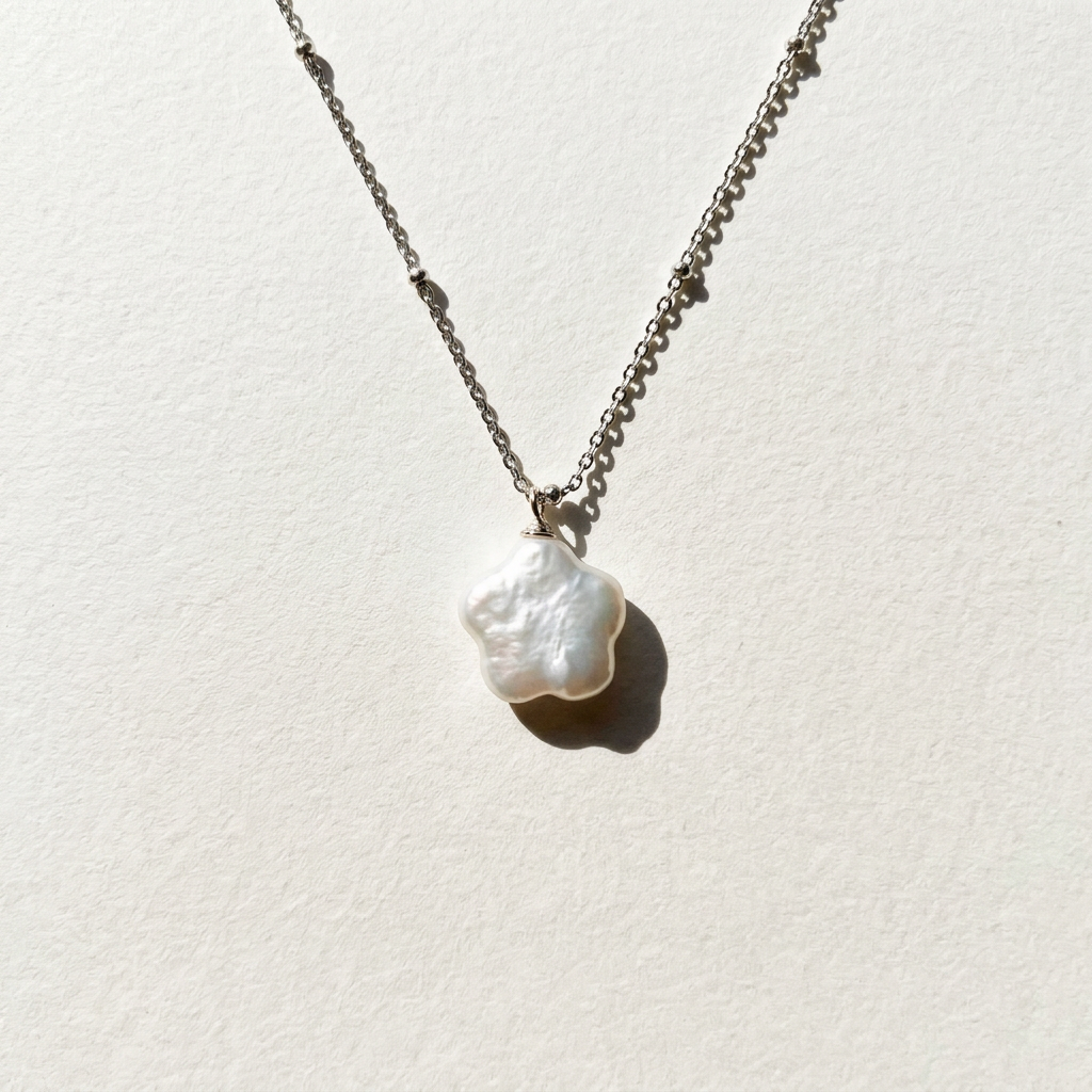 Close-up of the star baroque freshwater pearl pendant necklace in sterling silver on a light beige background