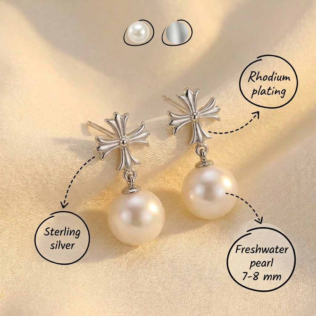 The Crosslight pearl drop earrings in sterling silver with imitation pearl drops and material notes on a warm beige fabric background