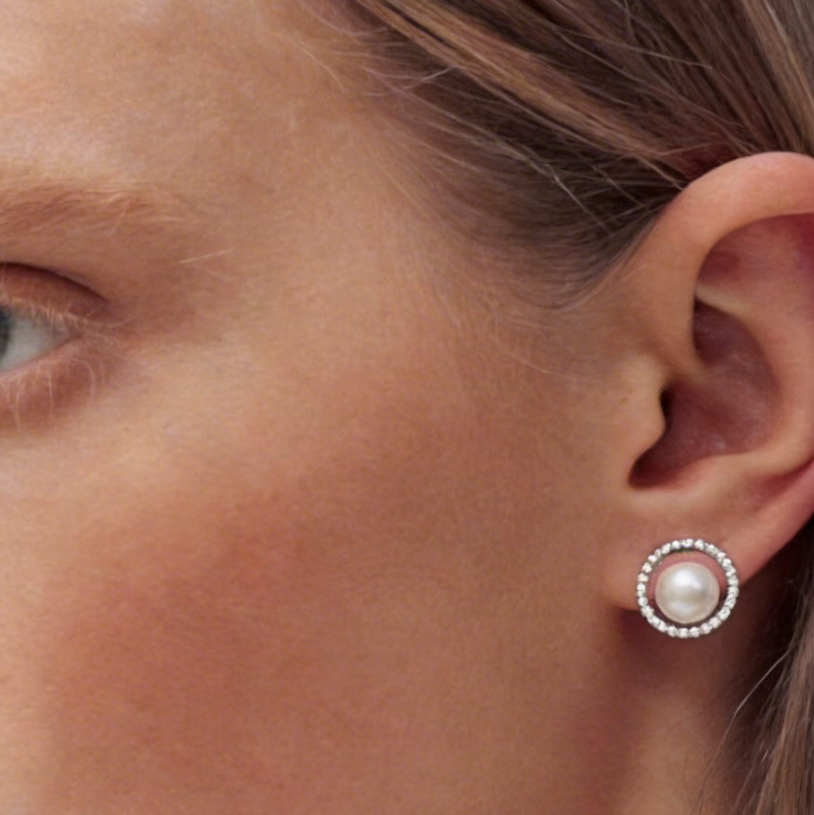 Close-up of The Halo Pearl zircon-set stud earring with a freshwater pearl worn on the ear