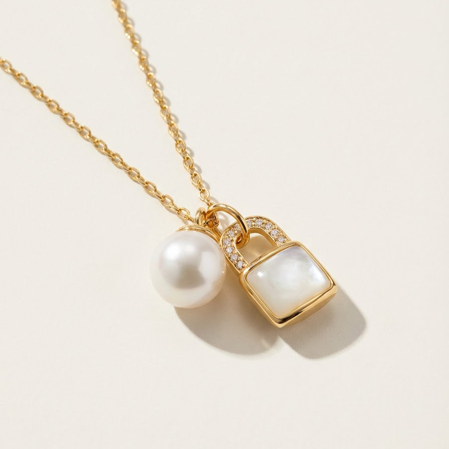 The Keeper’s Whisper necklace with a mother-of-pearl lock pendant and freshwater pearl shown on a light background