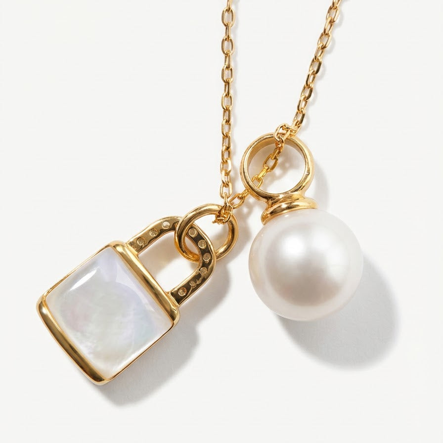 Close-up of The Keeper’s Whisper necklace showing the mother-of-pearl lock pendant and freshwater pearl
