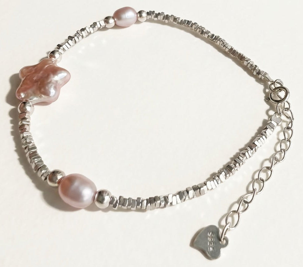 The Lavender Star sterling silver bracelet with lavender baroque pearls, star charm, and extender chain on a light background