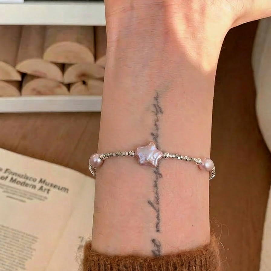 The Lavender Star baroque pearl and star charm bracelet worn on the wrist
