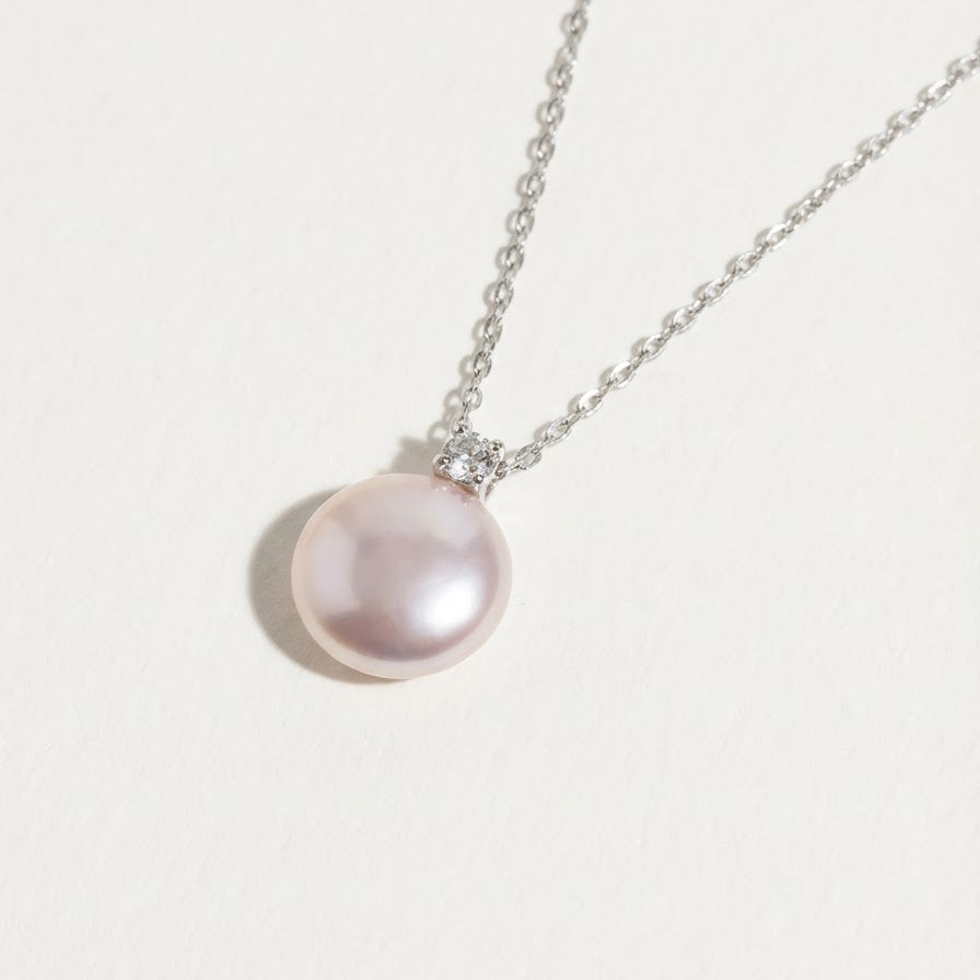 Close-up of The Moondrop button pearl pendant necklace with a round baroque freshwater pearl and sterling silver setting