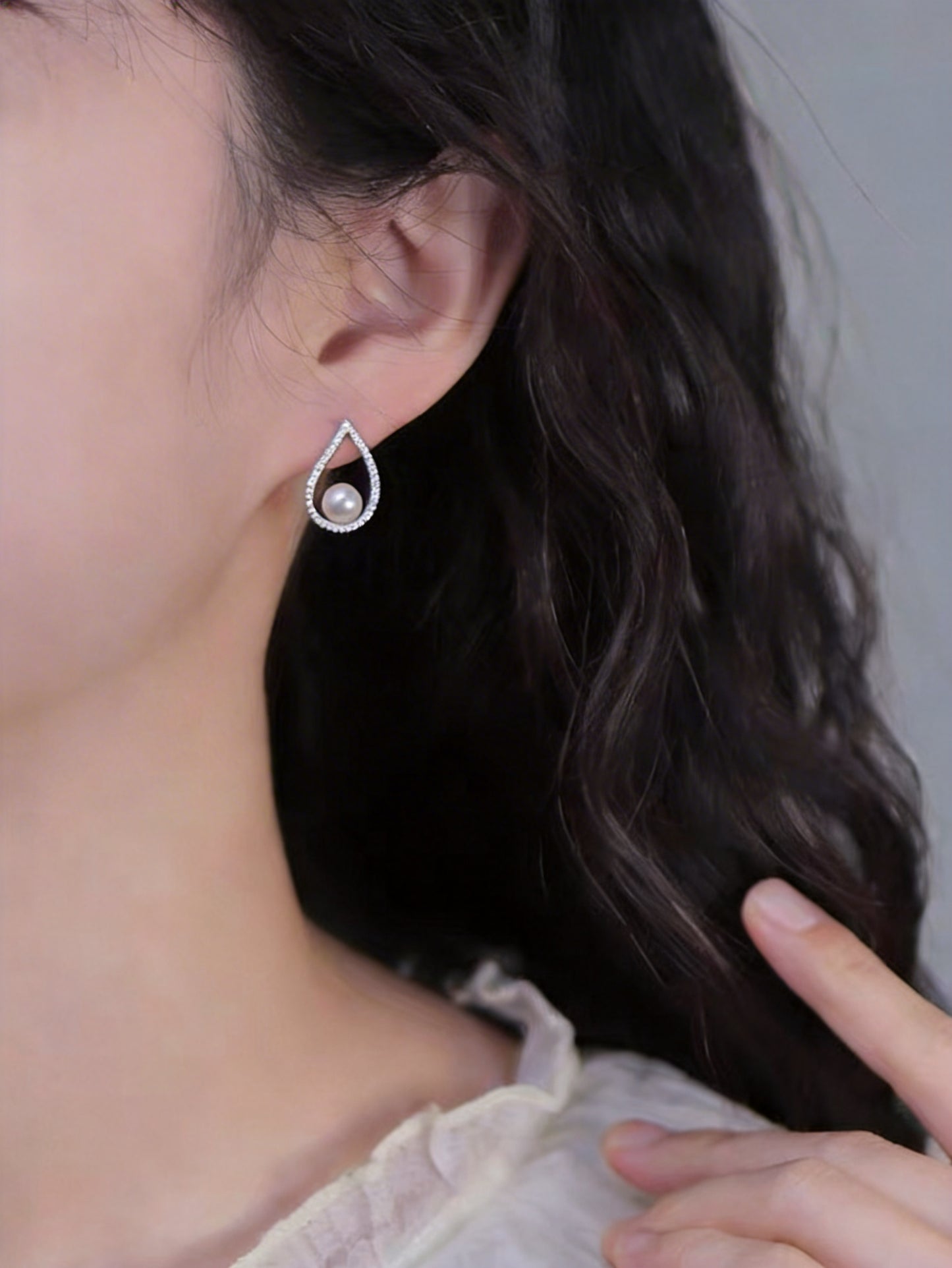 Close-up of The Quiet Drop pearl zircon stud earring with a freshwater pearl worn on the ear