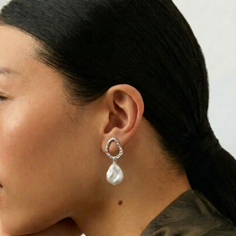 The Silver Drift baroque pearl drop earrings worn on the ear in side profile
