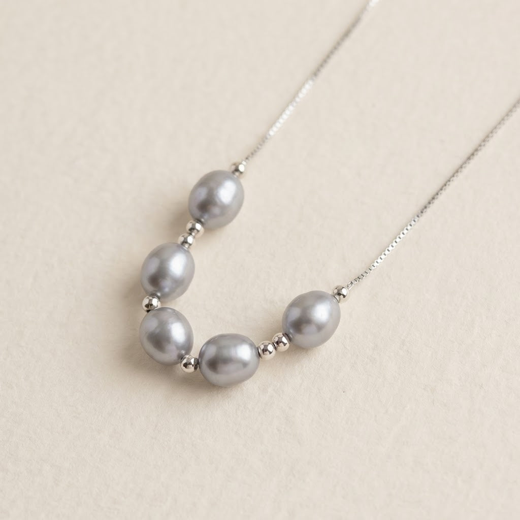 Close-up of The Silver Mist grey baroque pearl necklace with sterling silver beads on a light background