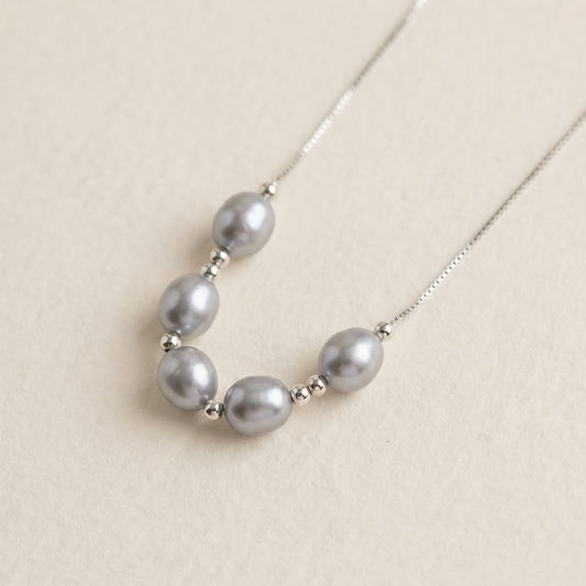 Close-up of The Silver Mist grey baroque pearl necklace with sterling silver beads on a light background