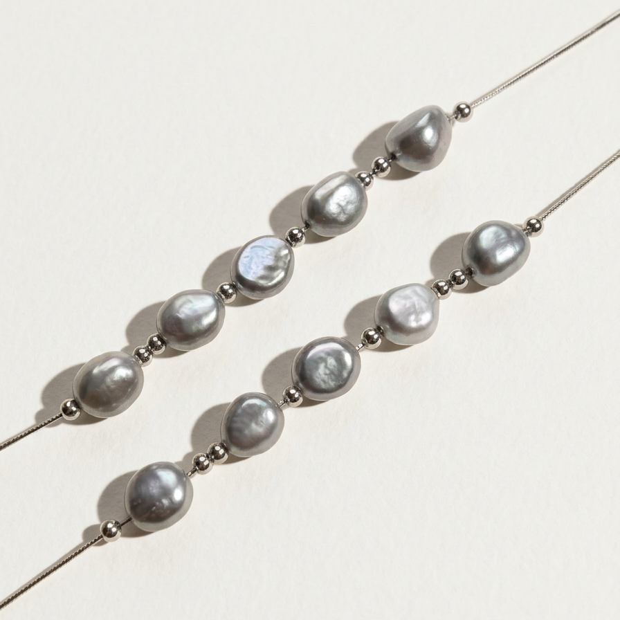 Diagonal close-up of The Silver Mist grey baroque pearl necklace with sterling silver beads on a light background