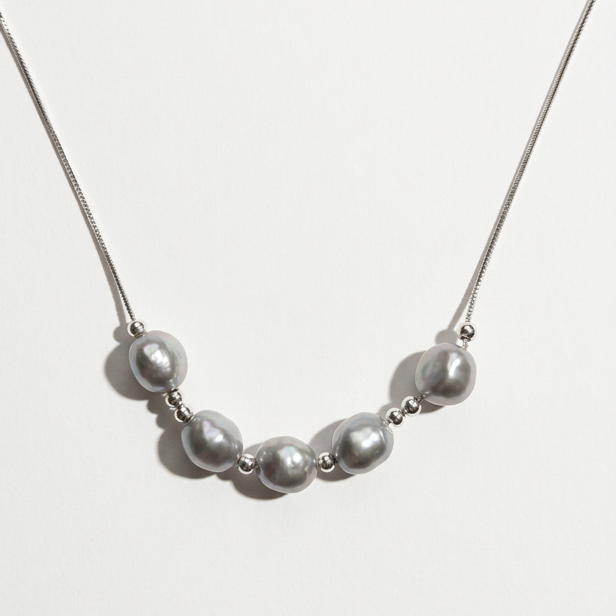 Front view of The Silver Mist grey baroque pearl necklace with sterling silver beads on a light background
