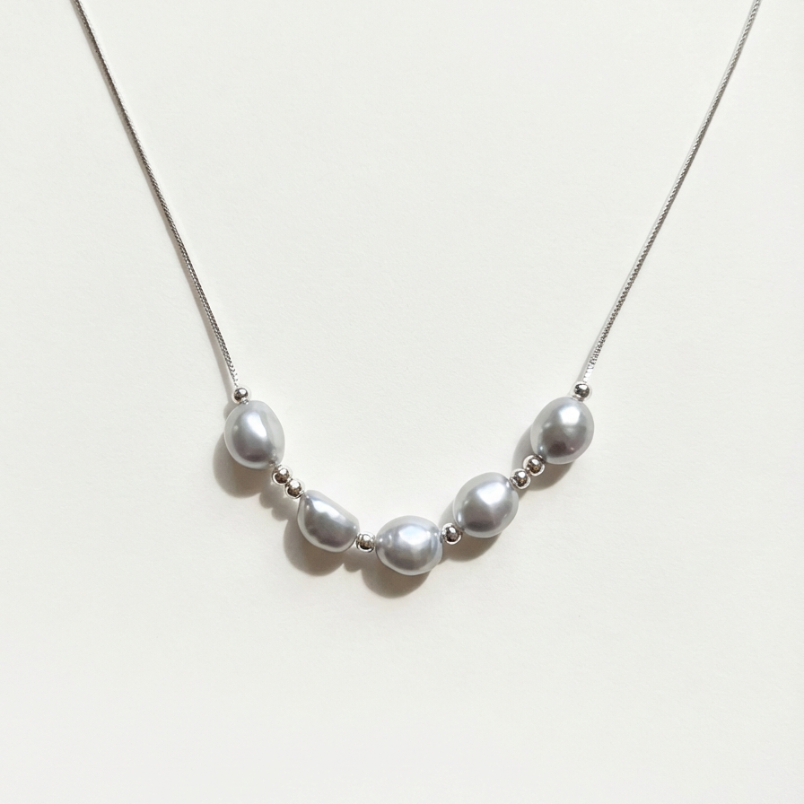 The Silver Mist grey baroque pearl necklace with sterling silver beads on a light background