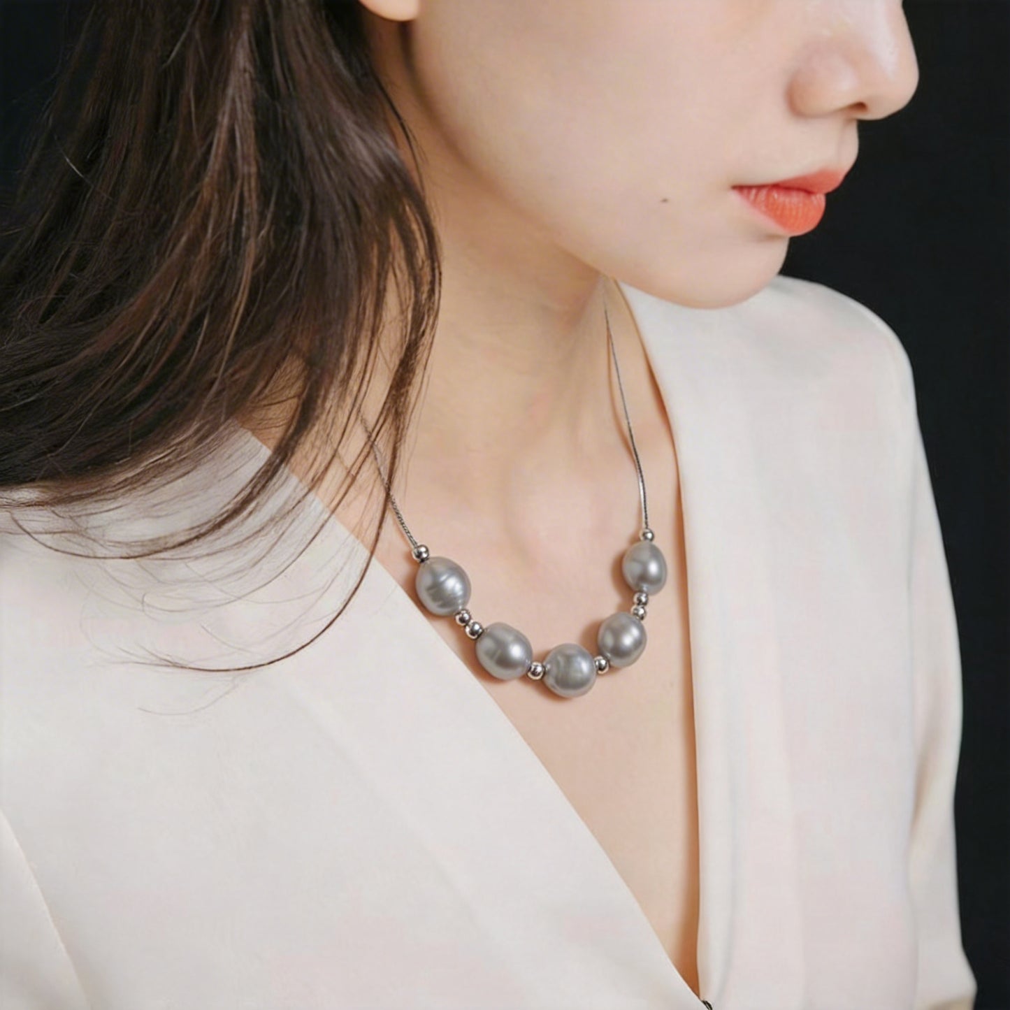 Close-up of The Silver Mist grey baroque pearl necklace worn on the neck