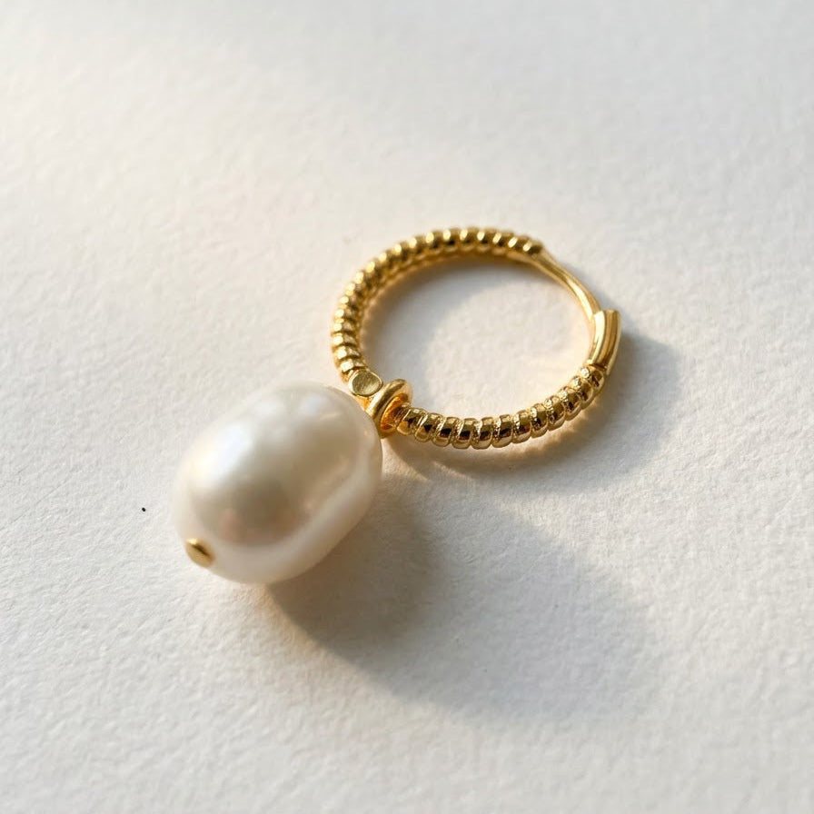 The Soft Hoop freshwater pearl huggie earring in gold-plated sterling silver with a pearl drop on a light grey background