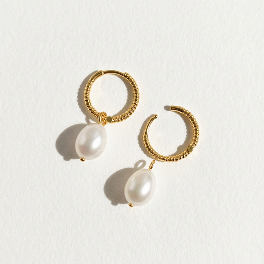 The Soft Hoop freshwater pearl huggie earrings in gold-plated sterling silver with pearl drops on a light grey background