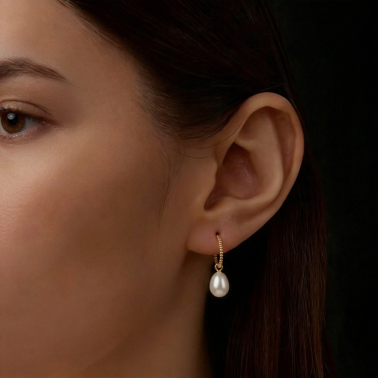 The Soft Hoop freshwater pearl huggie earring worn on the ear in gold-plated sterling silver with a pearl drop