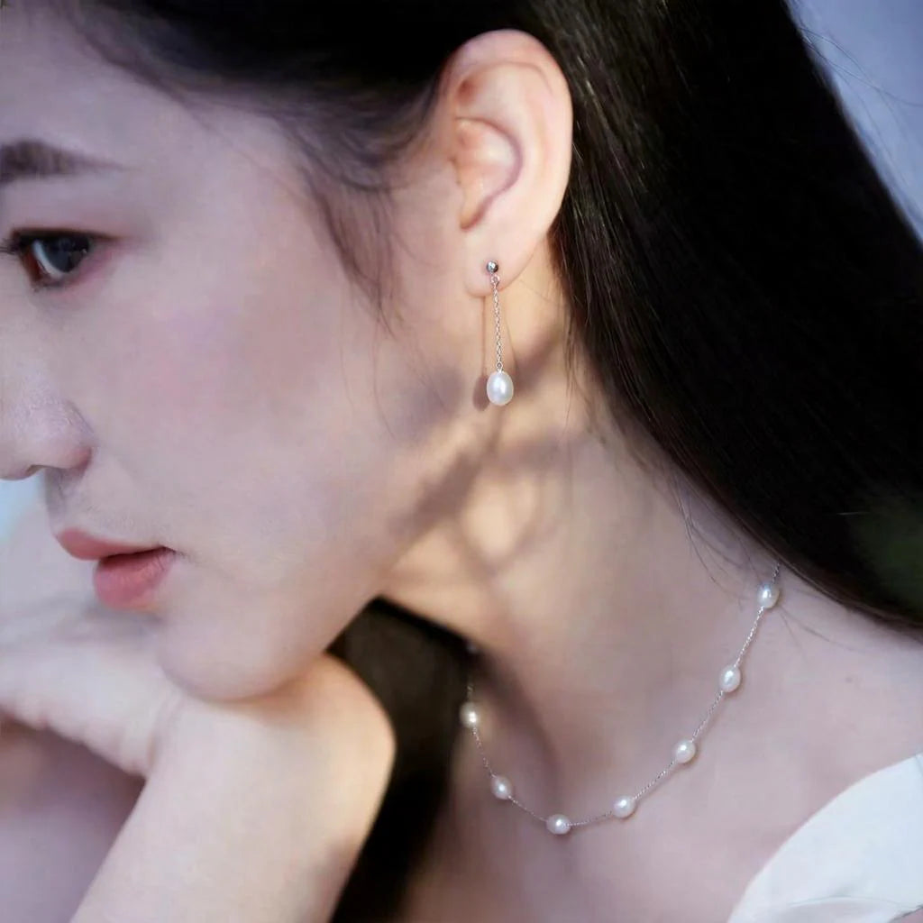 The Stardust Path necklace worn on the neck and shown together with matching pearl earrings