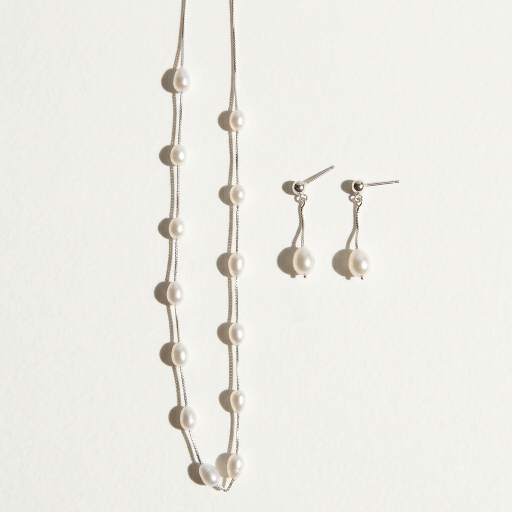 The Stardust Path necklace shown together with matching pearl earrings on a light background