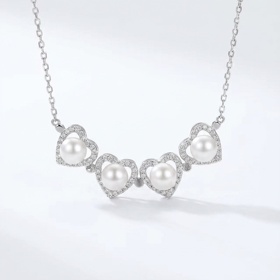 The Turning Heart necklace in sterling silver with four freshwater pearls framed by pavé zirconia on a light grey background