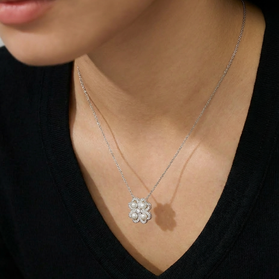 The Turning Heart necklace worn at the neckline in sterling silver with four freshwater pearls framed by pavé zirconia
