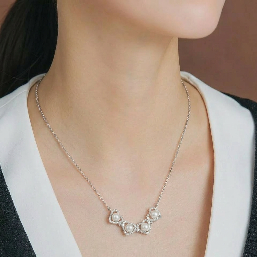 The Turning Heart necklace worn at the neckline in sterling silver with four freshwater pearls framed by pavé zirconia